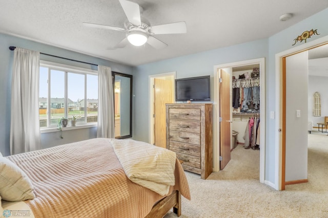 bedroom featuring ceiling fan, light colored carpet, baseboards, a closet, and a spacious closet