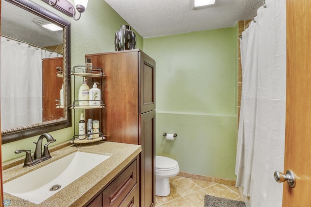 bathroom with tile patterned flooring, a textured ceiling, toilet, and vanity