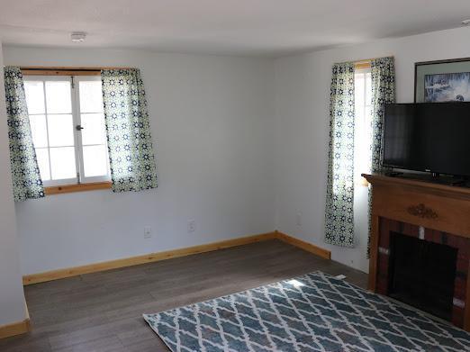 unfurnished living room with a fireplace, wood finished floors, and baseboards