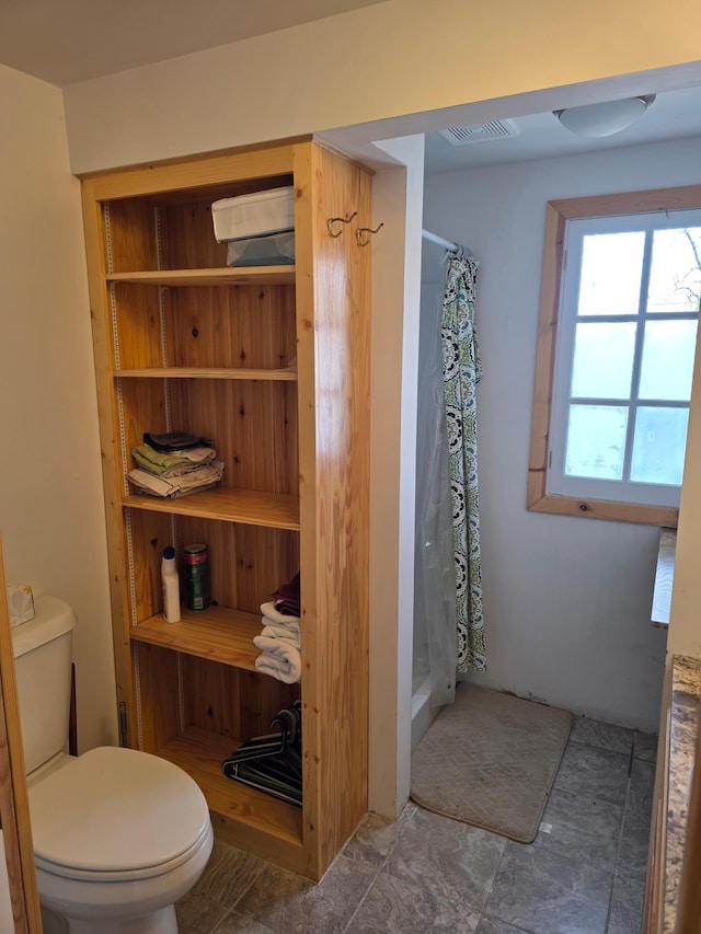 bathroom featuring curtained shower, toilet, and visible vents