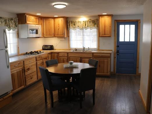 kitchen with a sink, light countertops, dark wood-style flooring, recessed lighting, and white appliances