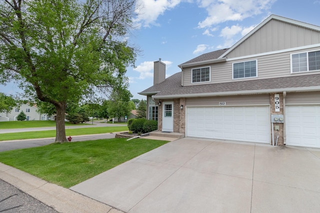 905 106th Ln NW Unit 82, Coon Rapids, MN 55433 - view of front of home with a front lawn, concrete driveway, a chimney, a shingled roof, and board and batten siding