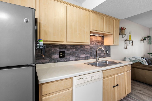 kitchen with light brown cabinetry, a sink, and freestanding refrigerator