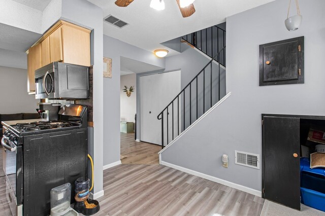 interior space featuring baseboards, visible vents, a ceiling fan, and light wood-style floors