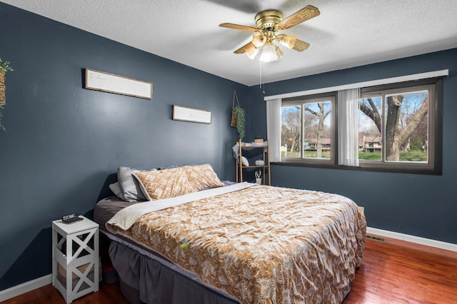bedroom with visible vents, wood finished floors, and baseboards