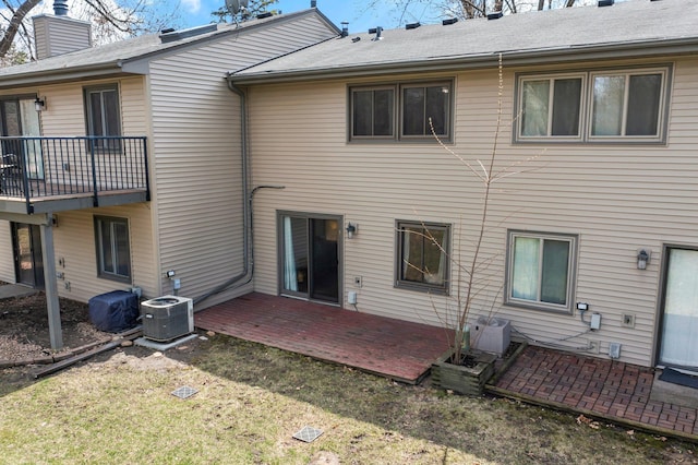rear view of house featuring a patio area, a lawn, central AC, a chimney, and a deck