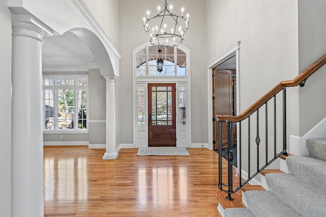 foyer with ornate columns, arched walkways, baseboards, and wood finished floors