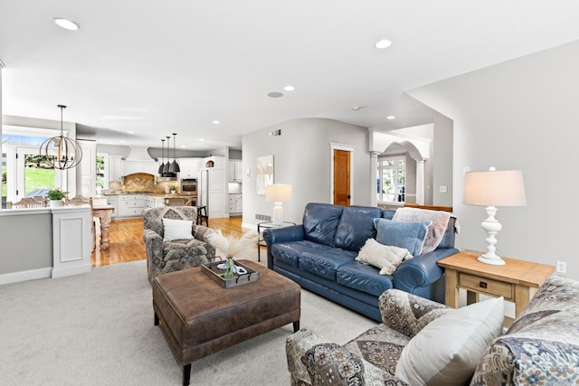 living room featuring an inviting chandelier, arched walkways, decorative columns, and recessed lighting