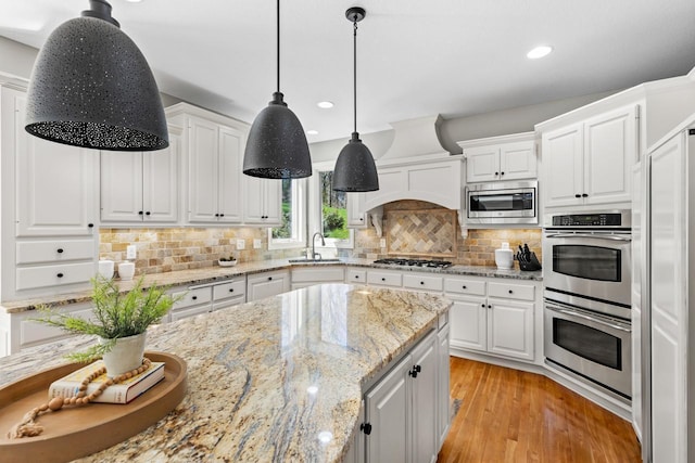 kitchen with a sink, white cabinetry, light wood-style flooring, and stainless steel appliances