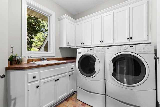 clothes washing area featuring a sink, cabinet space, and washer and clothes dryer