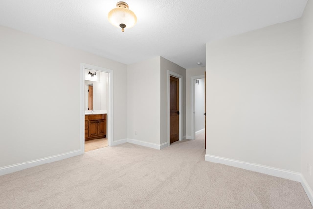 unfurnished room featuring baseboards, light carpet, and a textured ceiling
