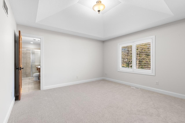 spare room featuring a raised ceiling, baseboards, carpet, and visible vents