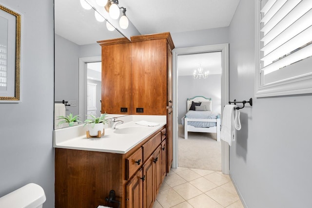 half bath featuring tile patterned flooring, vanity, toilet, an inviting chandelier, and ensuite bath