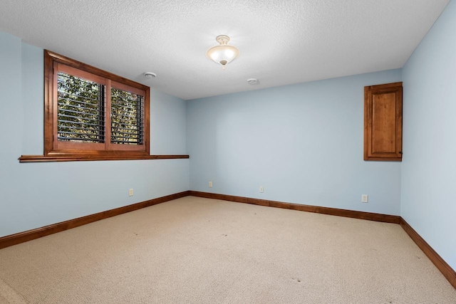 unfurnished room featuring baseboards, a textured ceiling, and light colored carpet