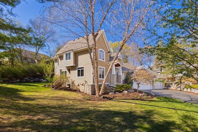 view of side of property with a yard, driveway, and roof with shingles