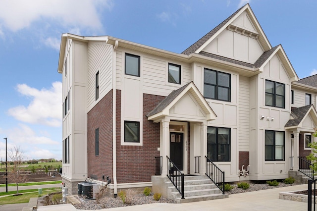 townhome / multi-family property featuring board and batten siding, brick siding, central AC, and entry steps