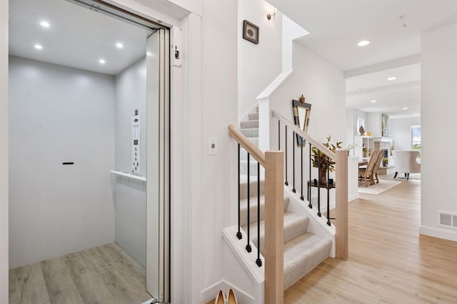 stairs featuring recessed lighting, elevator, wood finished floors, and visible vents