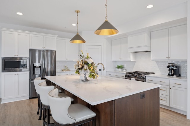 kitchen featuring a center island with sink, recessed lighting, white cabinets, a sink, and stainless steel appliances