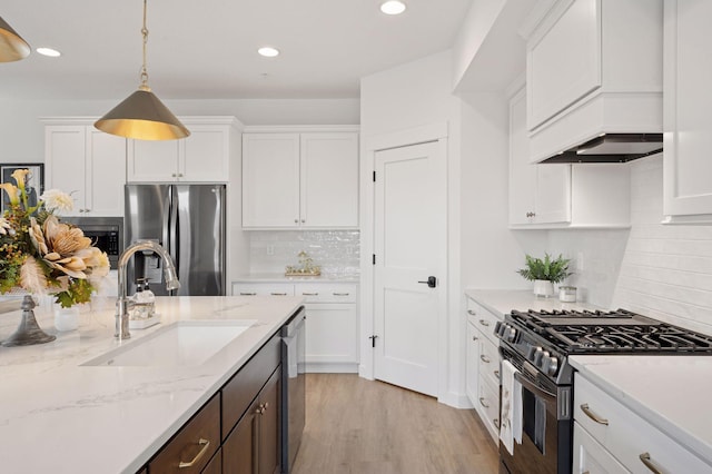 kitchen with decorative backsplash, pendant lighting, a sink, stainless steel appliances, and white cabinetry