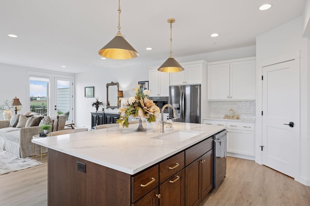 kitchen with appliances with stainless steel finishes, light wood-type flooring, a sink, recessed lighting, and white cabinetry
