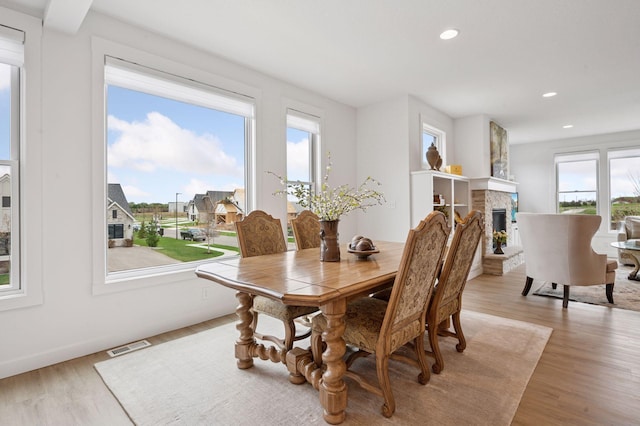 dining room featuring recessed lighting, visible vents, a stone fireplace, and light wood-style flooring