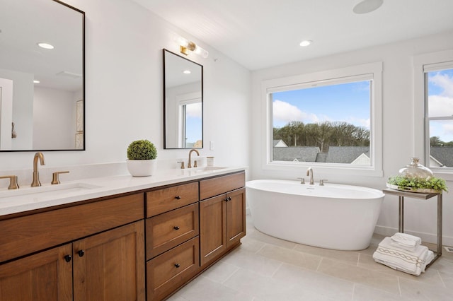 bathroom featuring double vanity, a freestanding tub, a sink, and tile patterned flooring