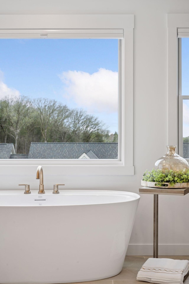 full bath with a freestanding bath, baseboards, and tile patterned floors