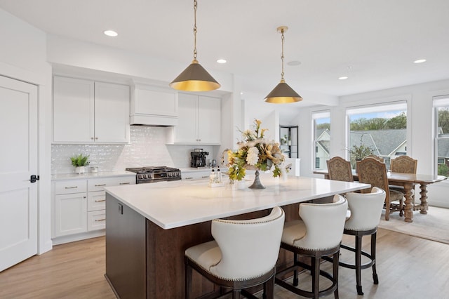 2301 Simply Living Ln, Hudson, WI 54016 - kitchen with light wood-type flooring, a kitchen island, backsplash, white cabinetry, and recessed lighting