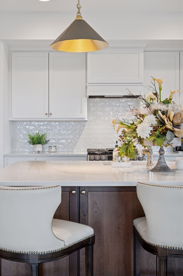 2301 Simply Living Ln, Hudson, WI 54016 - kitchen with white cabinetry, tasteful backsplash, stainless steel range with gas stovetop, and a breakfast bar
