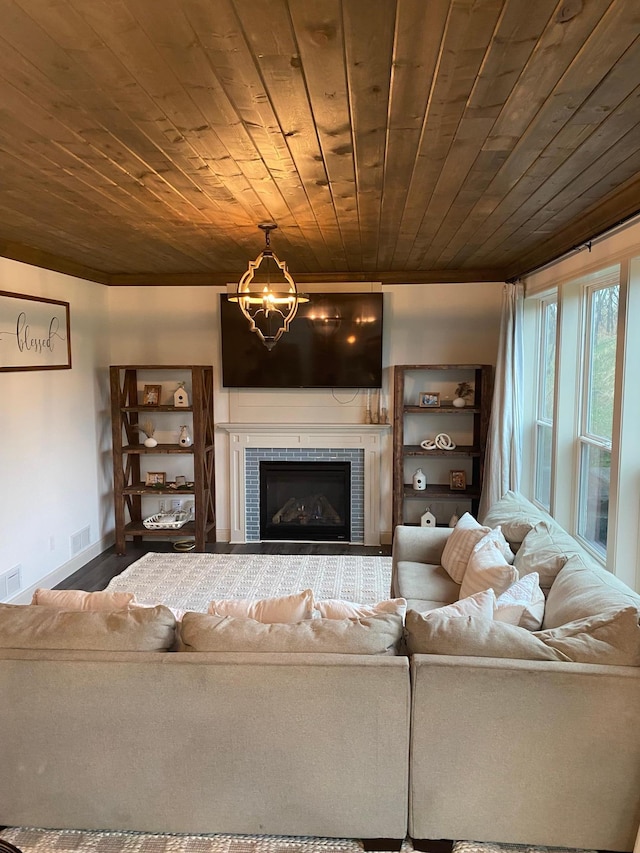 living room with wood ceiling, visible vents, crown molding, a tile fireplace, and baseboards