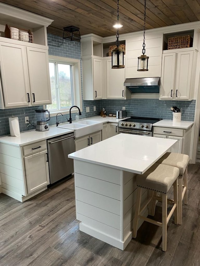 kitchen featuring a sink, light countertops, stainless steel appliances, a kitchen island, and wood ceiling