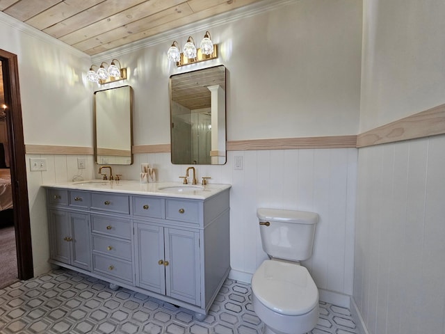 bathroom featuring a sink, a wainscoted wall, toilet, and wooden ceiling