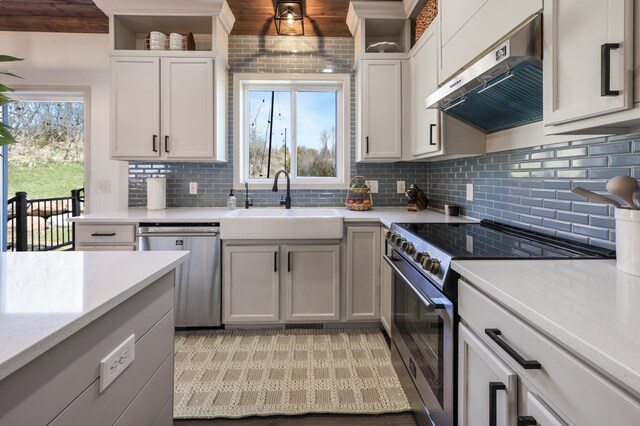 kitchen featuring exhaust hood, appliances with stainless steel finishes, a sink, light countertops, and backsplash
