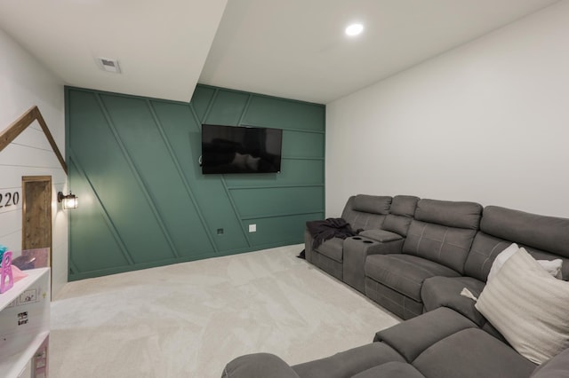 living area featuring visible vents, a decorative wall, and light carpet