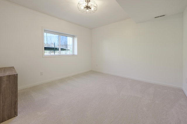 spare room with baseboards, light colored carpet, and visible vents