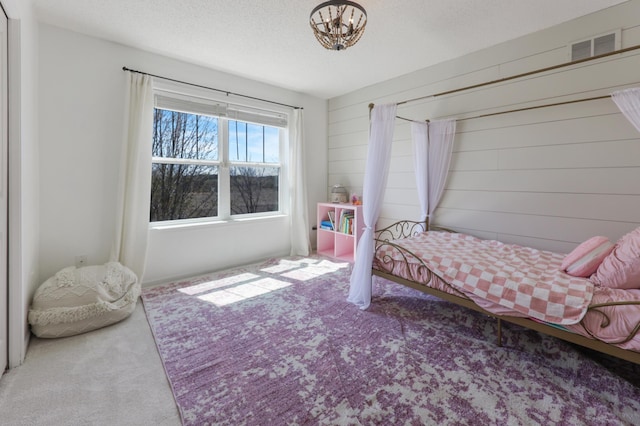 bedroom with visible vents, carpet, a textured ceiling, and a notable chandelier