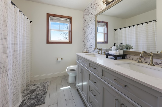full bath with plenty of natural light, a sink, and baseboards