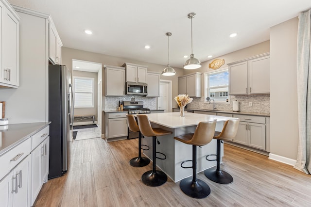 2133 Johanna Cir, Lino Lakes, MN 55038 - kitchen with stainless steel appliances, a sink, tasteful backsplash, light wood-style flooring, and a kitchen bar