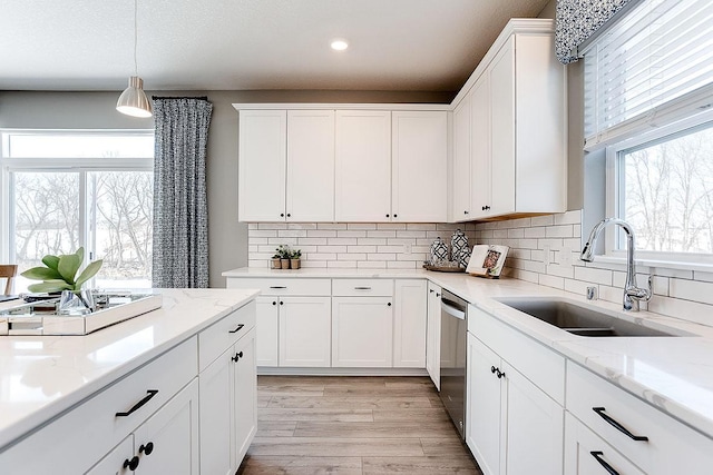 14234 Empire Ln N, Dayton, MN 55327 - kitchen featuring a sink, dishwasher, light wood-style floors, white cabinetry, and pendant lighting