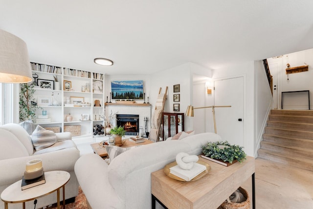 living area featuring a brick fireplace and stairway