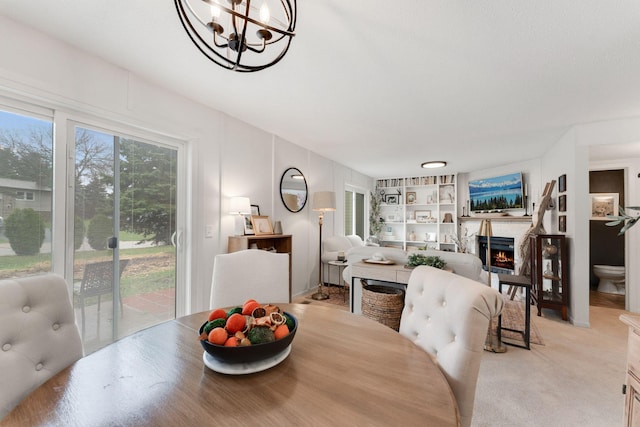dining room featuring a notable chandelier, built in features, and a warm lit fireplace
