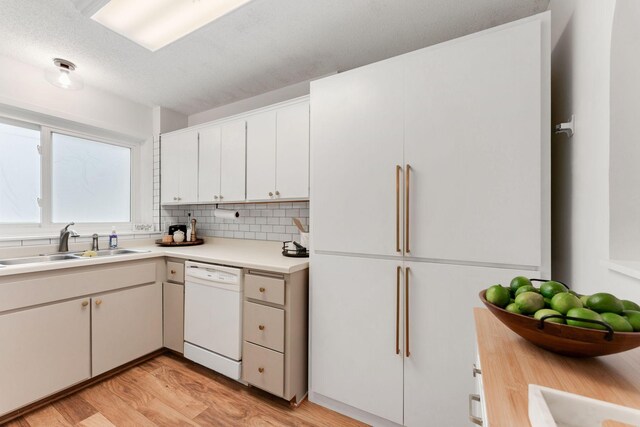 kitchen featuring a sink, white appliances, light wood-type flooring, backsplash, and light countertops