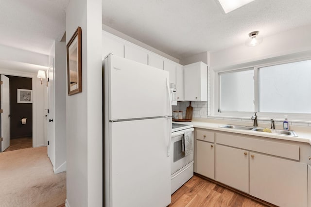kitchen with tasteful backsplash, white appliances, light countertops, a sink, and a textured ceiling
