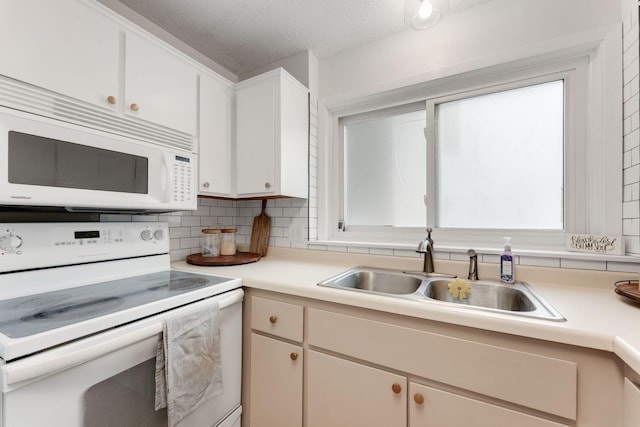 kitchen with a sink, white appliances, tasteful backsplash, light countertops, and a textured ceiling
