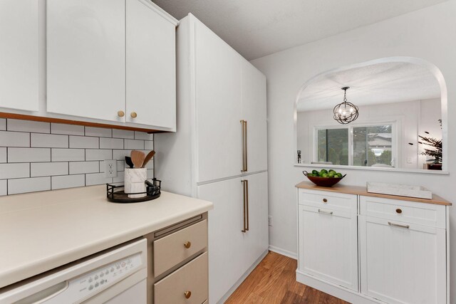kitchen featuring backsplash, light wood-style flooring, light countertops, dishwasher, and white cabinets