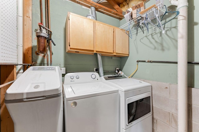 laundry area featuring independent washer and dryer, concrete block wall, and cabinet space