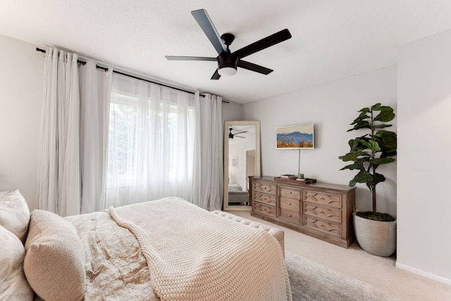 bedroom featuring ceiling fan, light colored carpet, and baseboards