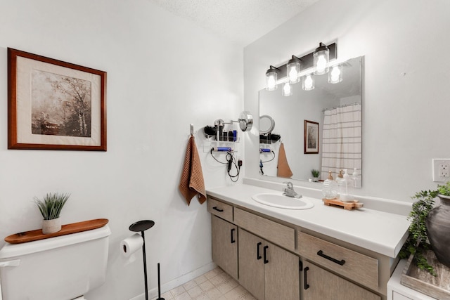 bathroom featuring baseboards, toilet, a textured ceiling, and vanity