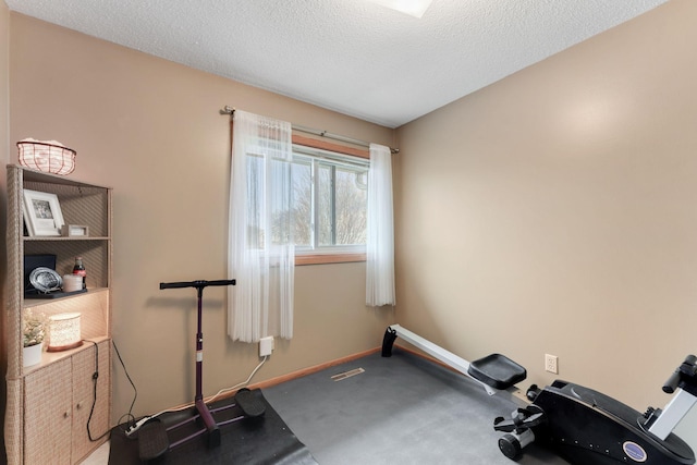 workout room with a textured ceiling, carpet floors, and baseboards