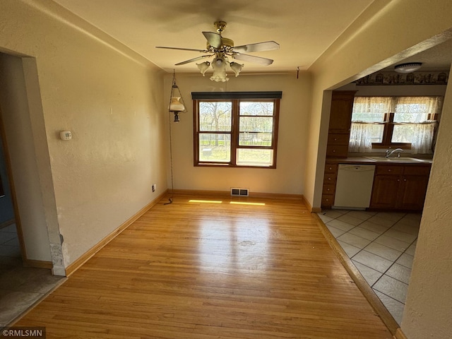 unfurnished dining area with a sink, a ceiling fan, visible vents, and light wood-type flooring